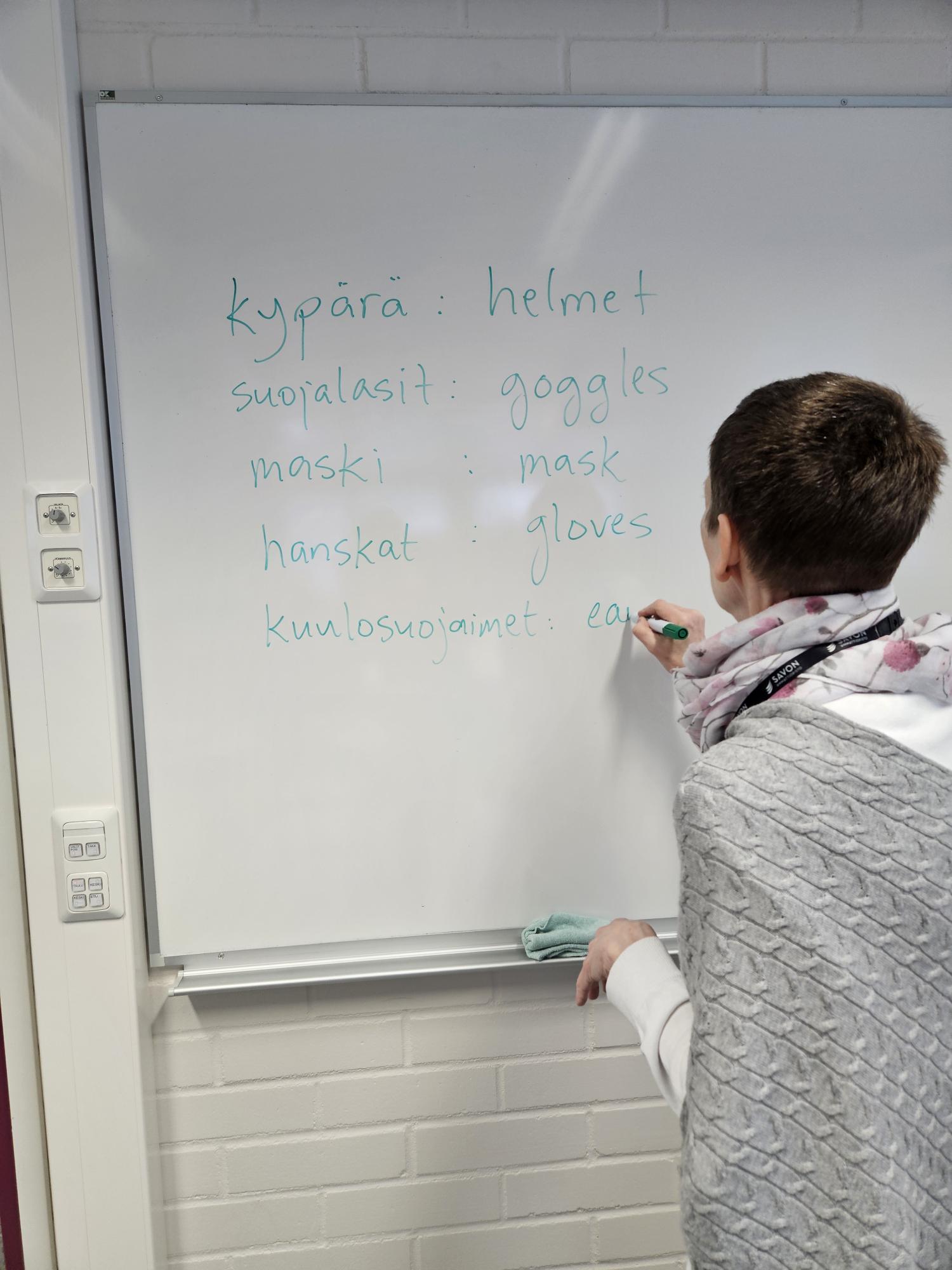 Opettaja kirjoittaa englanninkielisiä sanoja taululle.